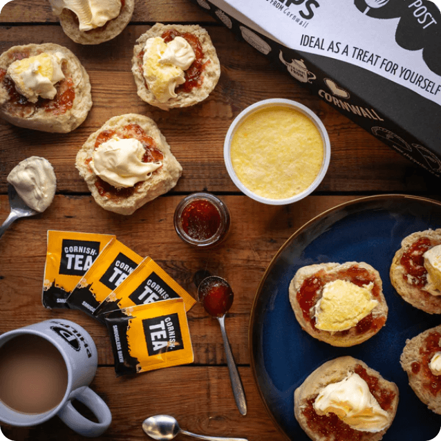 Scones topped with jam and clotted cream, a pot of tea and Cornish Tea sachets