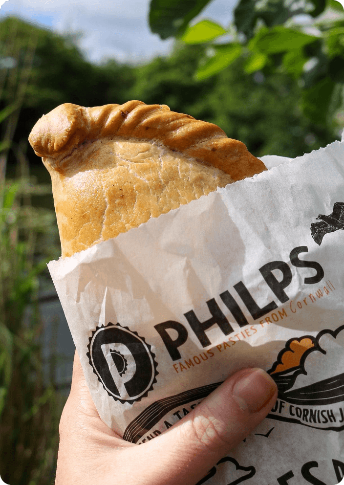 Pasty in Philps branded paper held outdoors against greenery