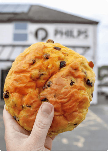 Hand holding a Cornish saffron bun outside the bakery