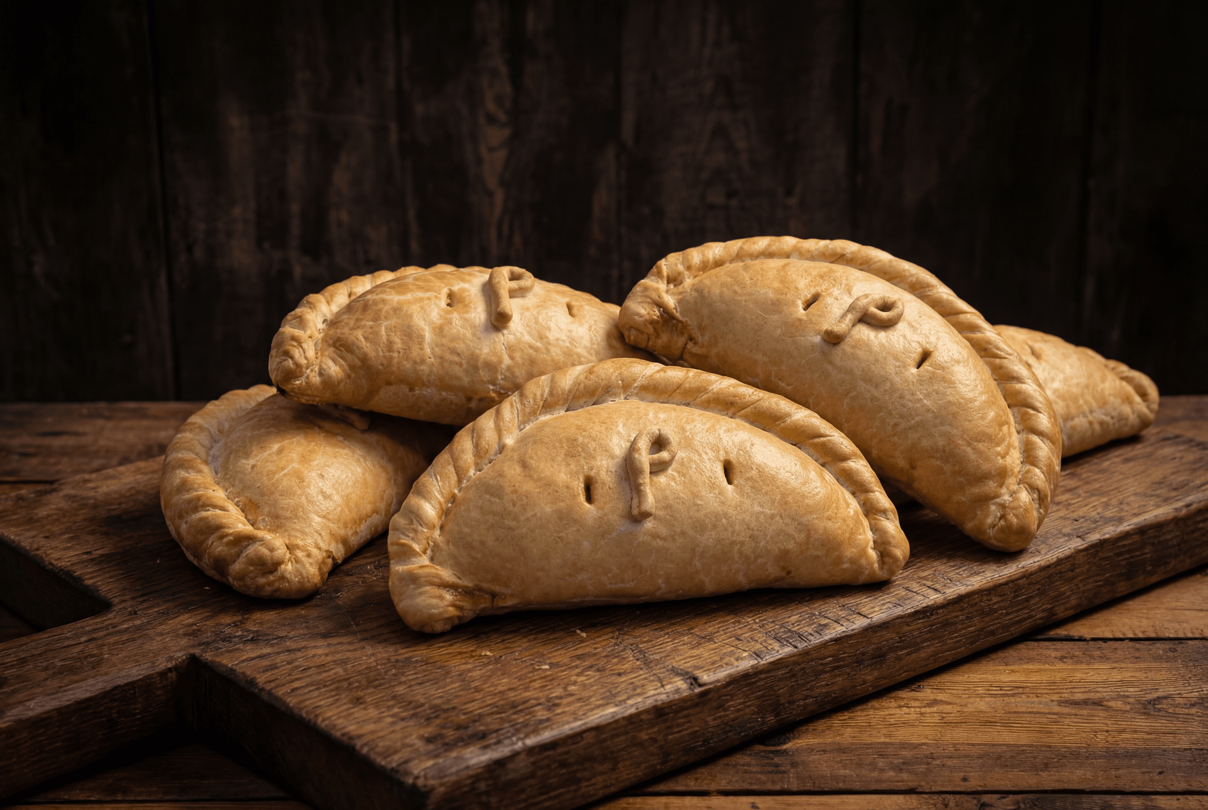 Family pasty box: a pile of freshly baked Philps Cornish pasties on a wooden board